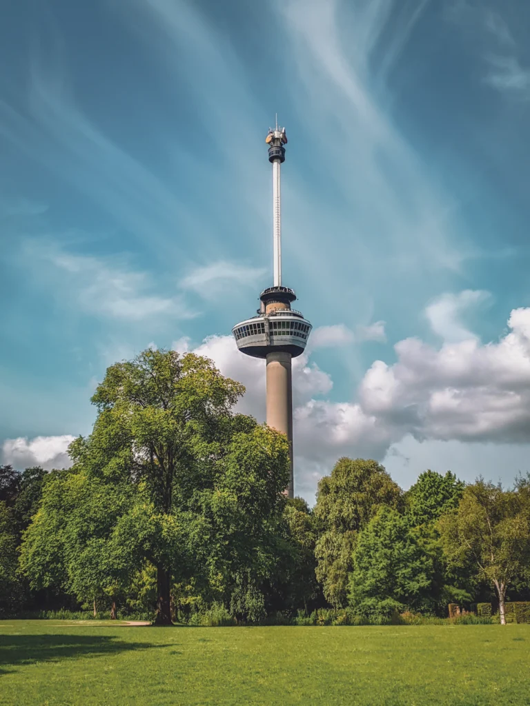 De Euromast in Rotterdam boven groene bomen en een grasveld